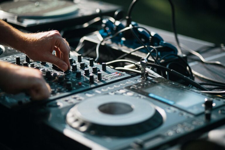 Close-up of a DJ mixing music on a turntable outdoors, capturing the art of sound mixing.