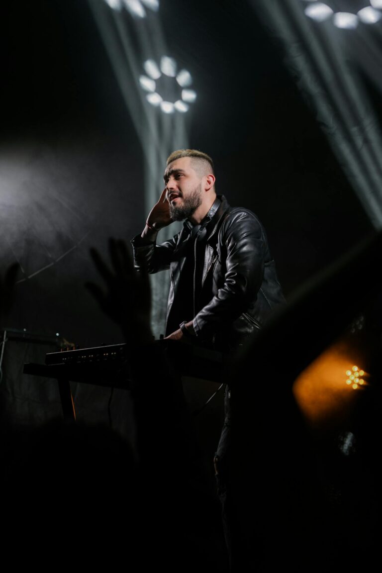 DJ performing on stage with vibrant lighting, engaging a lively audience.